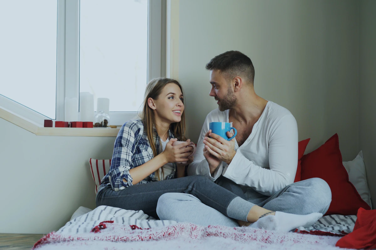 Couple qui discute tranquillement, assis sur un lit