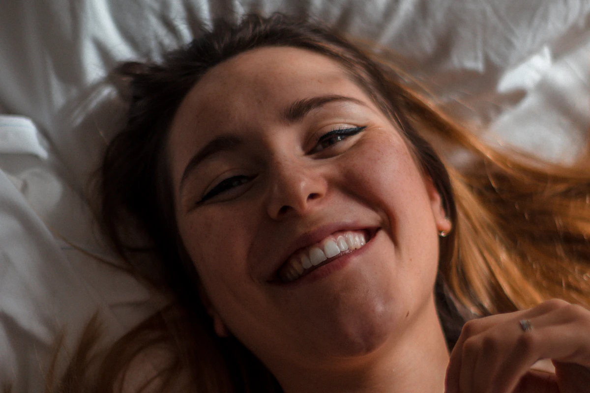 Femme radieuse allongée dans son lit, détendue et souriante