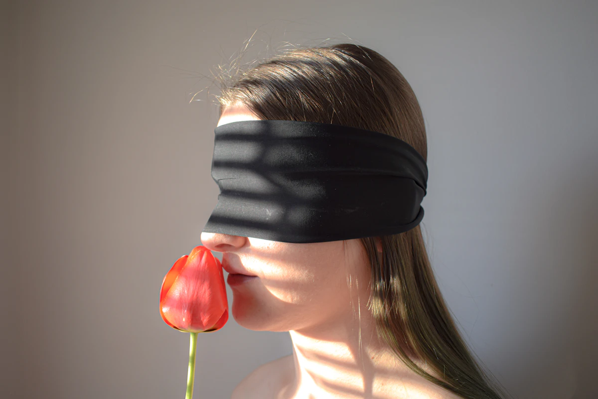 Femme aux yeux bandés qui respire une tulipe rouge, jeu de sensations