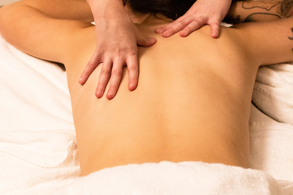 Mains qui massent le dos nu d'une femme allongée