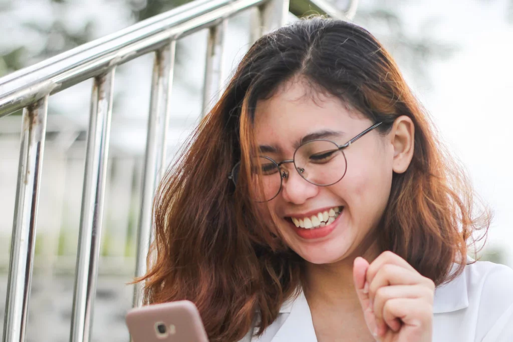 Femme qui rit en lisant un premier message sur un site de rencontre