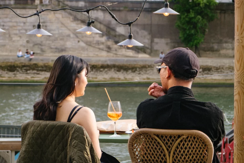 Couple qui prend un verre en terrasse au bord de l'eau pour un premier rendez-vous