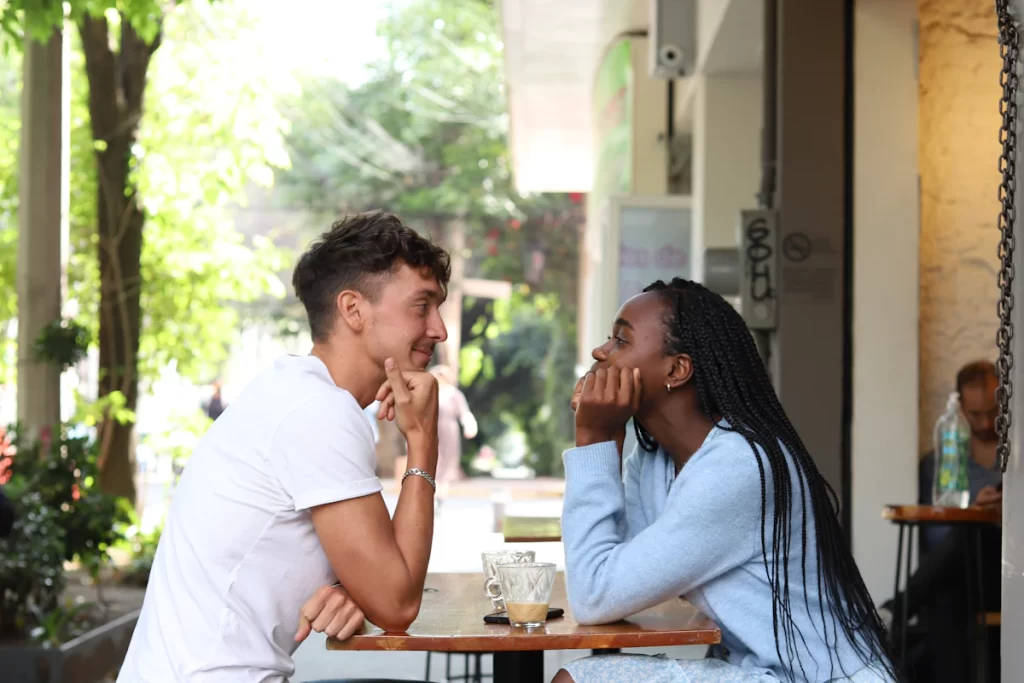 Homme et femme qui discutent et rient à la terrasse d'un café lors d'une première rencontre