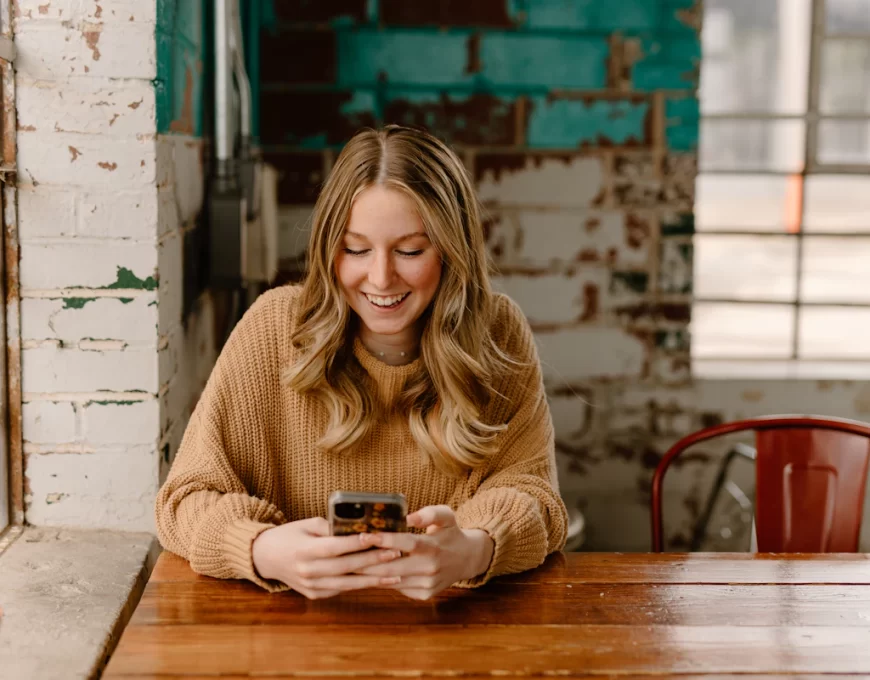 Femme souriante qui consulte une plateforme de rencontre sur son téléphone dans un café