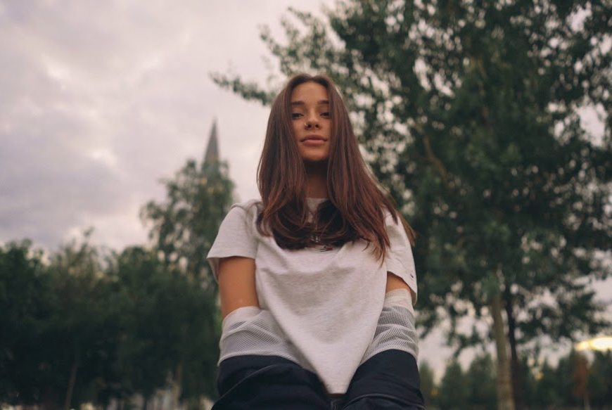 Femme assise dehors devant des arbres sous un ciel nuageux