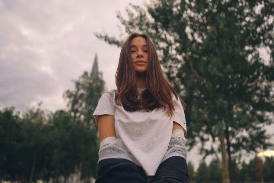 Femme assise dehors devant des arbres sous un ciel nuageux